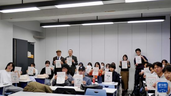 12月19日，在日本東京都的中央大學(xué)，學(xué)生們舉著自己制作的木版水印畫(huà)合影。新華社發(fā)